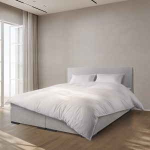 Boxspring opgemaakt in een trendy slaapkamer.