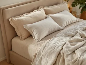 Luxe boxspring bed met beige teddystof bekleding, opgemaakt met dekbed en kussens in warme natuurtinten