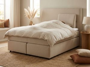Beige boxspring met hoofdbord en rugsteunkussen in warme slaapkamer met jute vloerkleed en natuurlijke verlichting