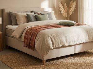 Boxspring bed met zachte topper, beige dekbed en natuurlijke kussens in rustgevende slaapkamer met aardetinten