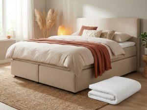 Boxspring bed met beige gestoffeerd frame en witte topper in warme slaapkamer met natuurlijke decoratie