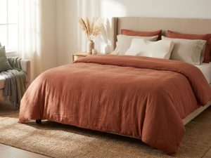 Slaapkamer met ergonomische hoofdkussens op bed met terracotta dekbed, demonstreert juiste nekondersteuning voor gezonde slaap