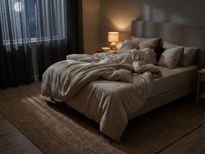 Persoon woelt rusteloos in bed met verfrommelde lakens tijdens slapeloze nacht in slaapkamer met maanlicht