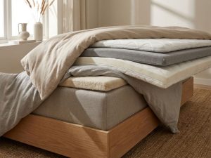 Drie topper diktes naast elkaar op boxspring bed, van dun naar dik, in warme beige tinten met natuurlijke belichting